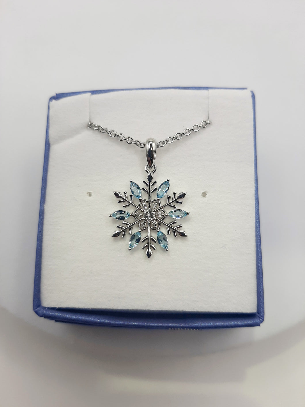 Sterling silver snowflake pendant featuring white and blue topaz